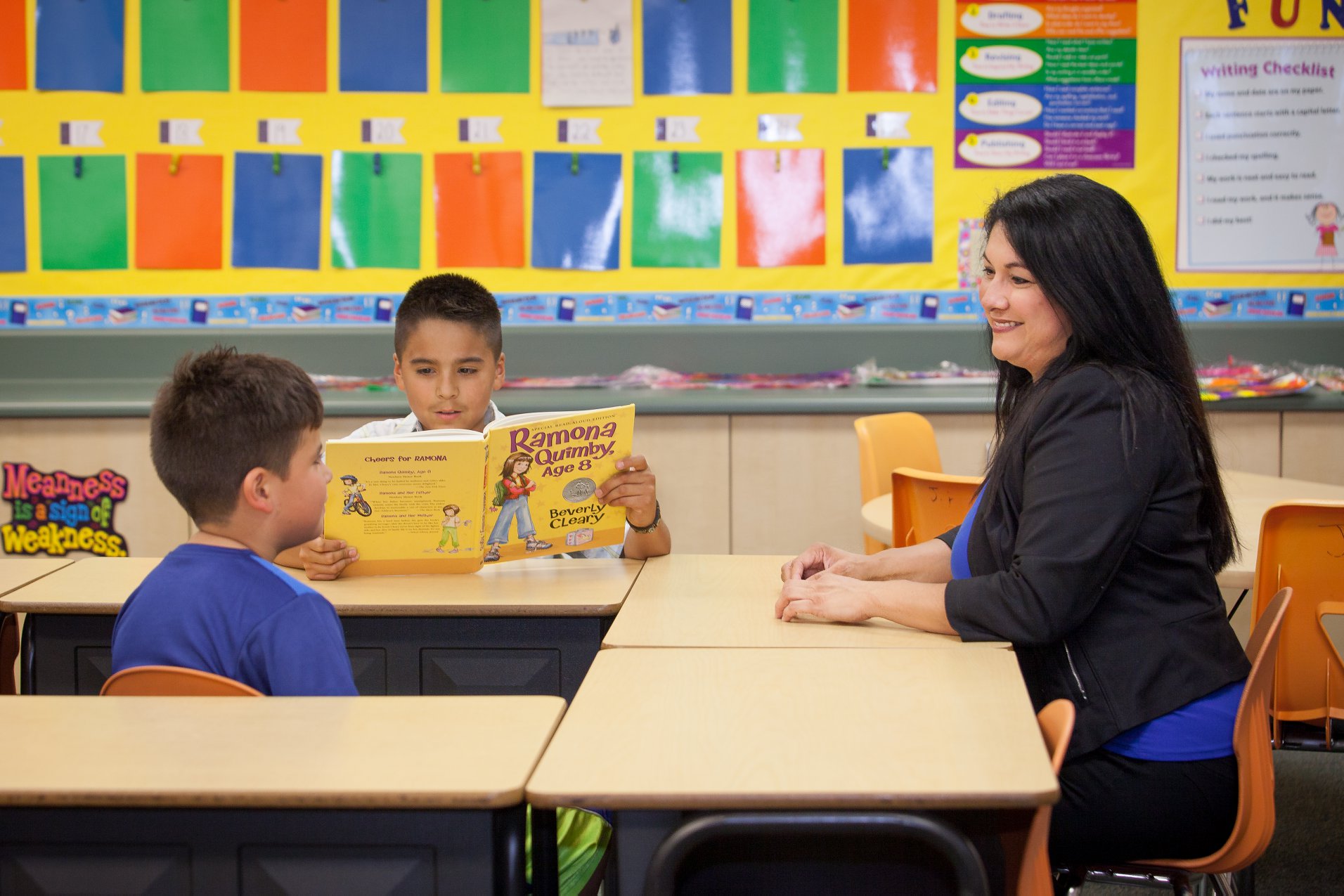 Kathryn visiting with students reading in a classroom