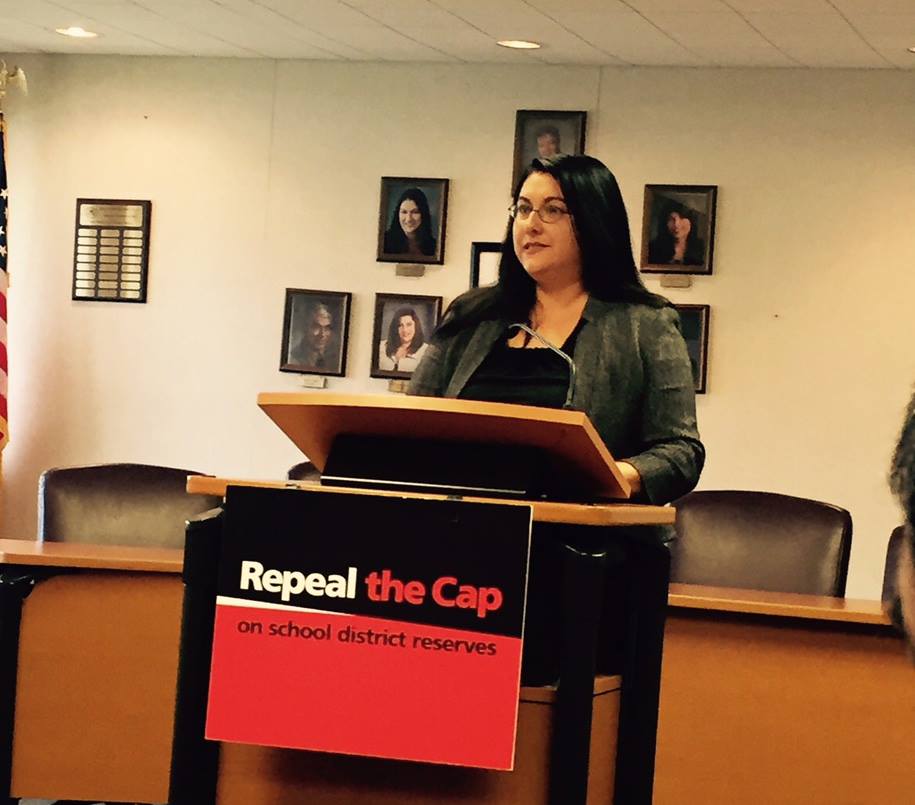 Kathryn addressing an audience from a podium about school district reserves